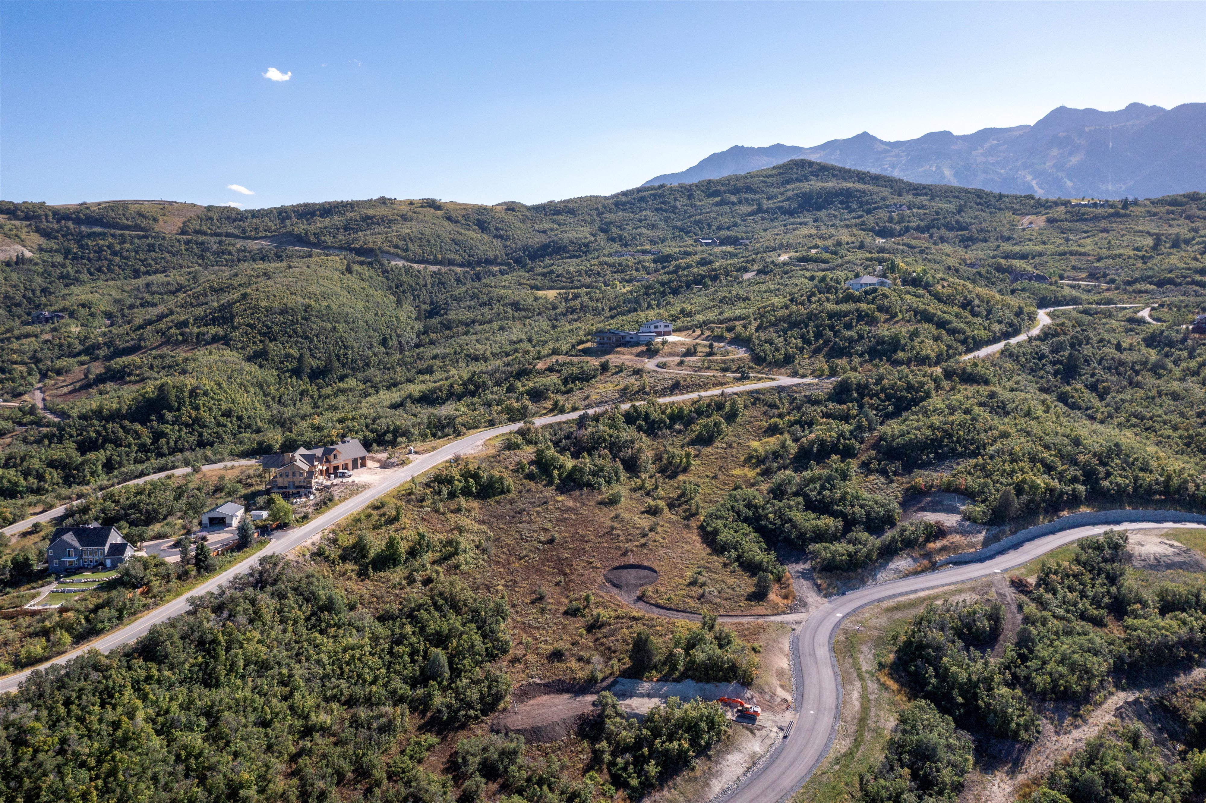 Expansive undeveloped land featuring a paved road, mountainous terrain, and abundant natural foliage
