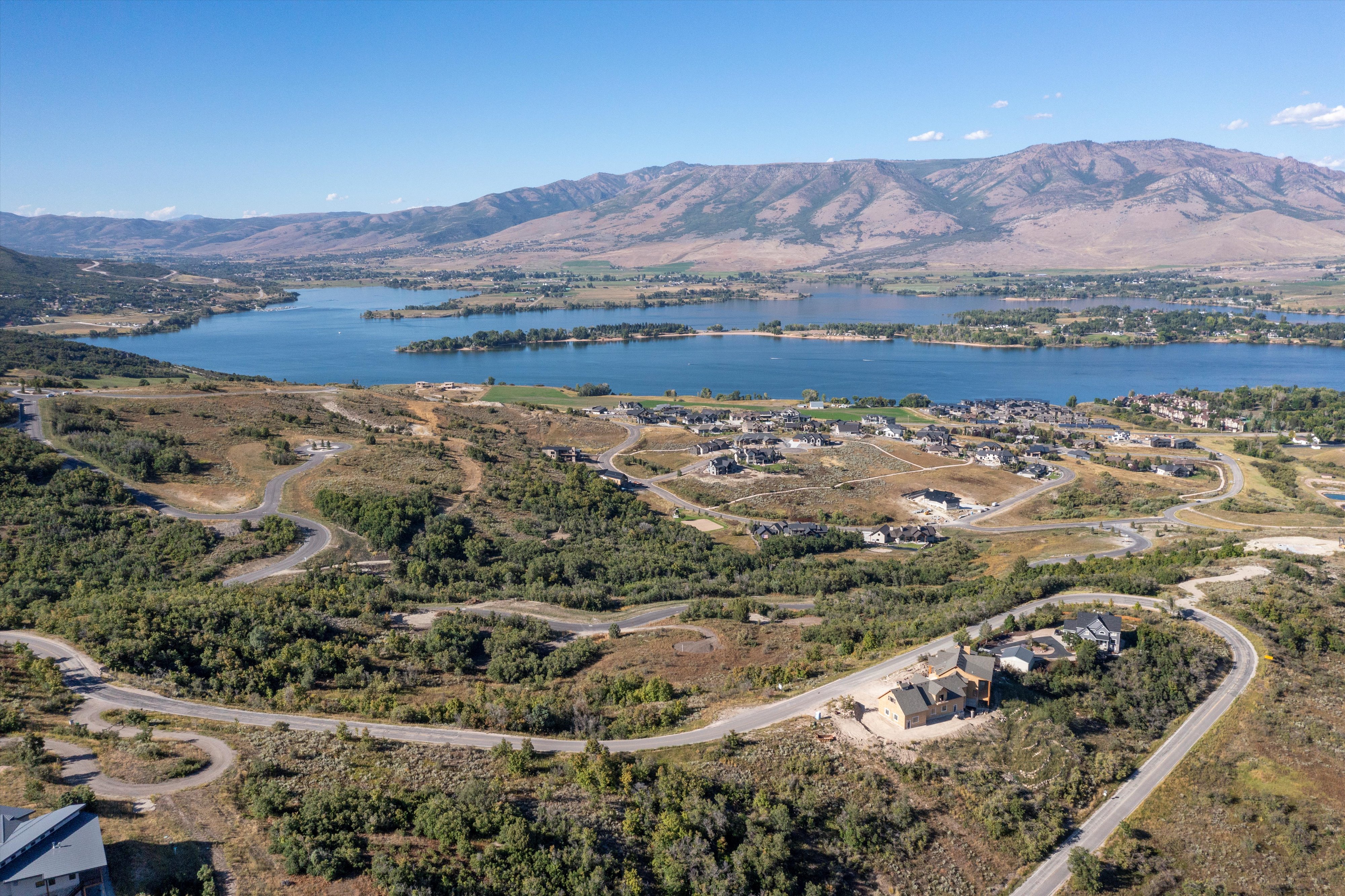Expansive development with winding paved roads and multiple residential structures, offering distant lake and mountain scenery