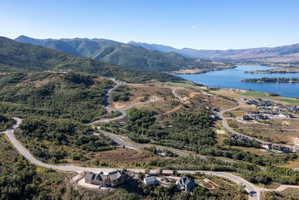Expansive mountain landscape featuring a large body of water, several residential properties, and winding roads