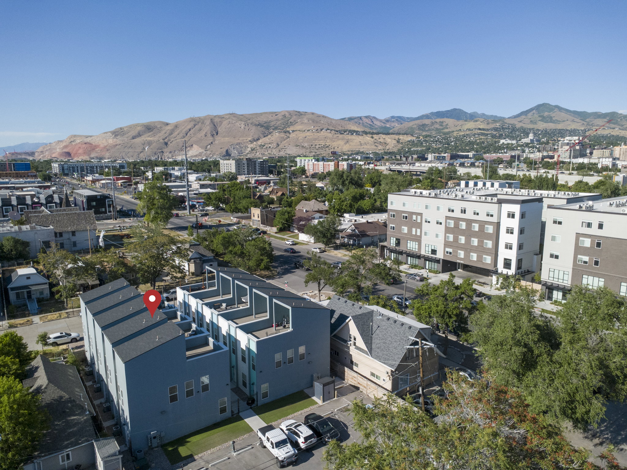 Modern multi-story residential building featuring a flat roofline, grey exterior siding, and multiple balconies