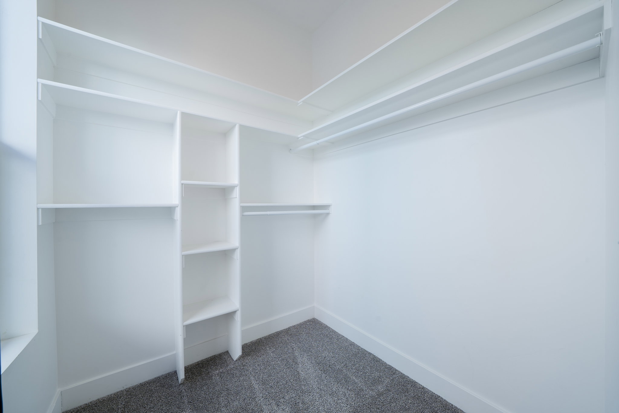 Built-in closet system featuring white shelving and clothing rods