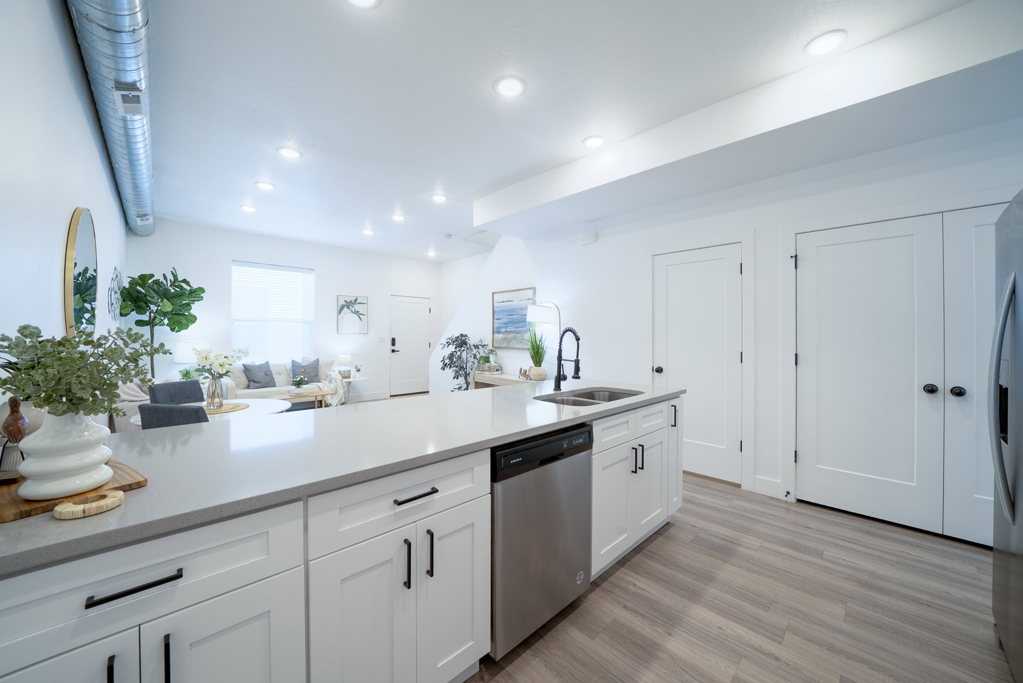 Kitchen island featuring a double-basin sink with a matte black faucet, integrated dishwasher, and under-counter storage with white shaker-style cabinetry and matte black hardware