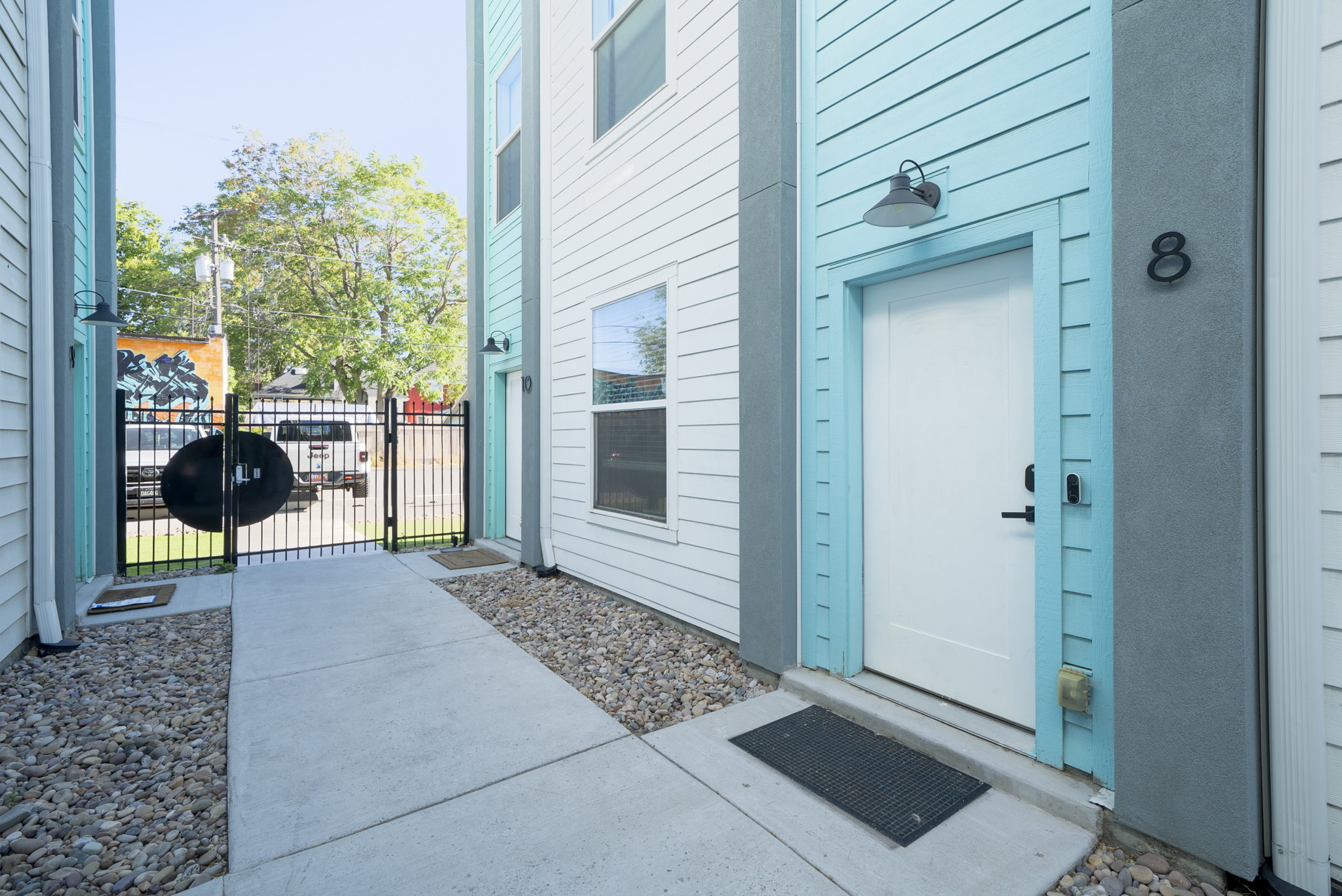 Contemporary exterior featuring light blue siding, white trim, and a prominent white entry door with contrasting black hardware