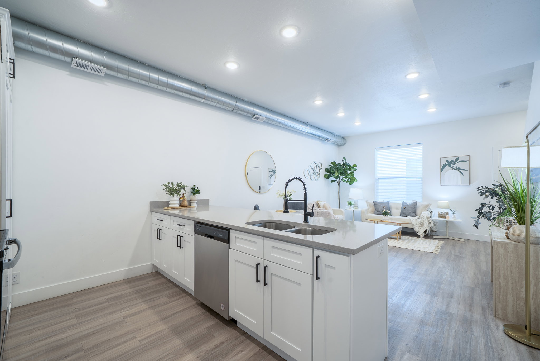 Kitchen island featuring a double-basin sink with a matte black faucet, integrated dishwasher, and light-toned countertop