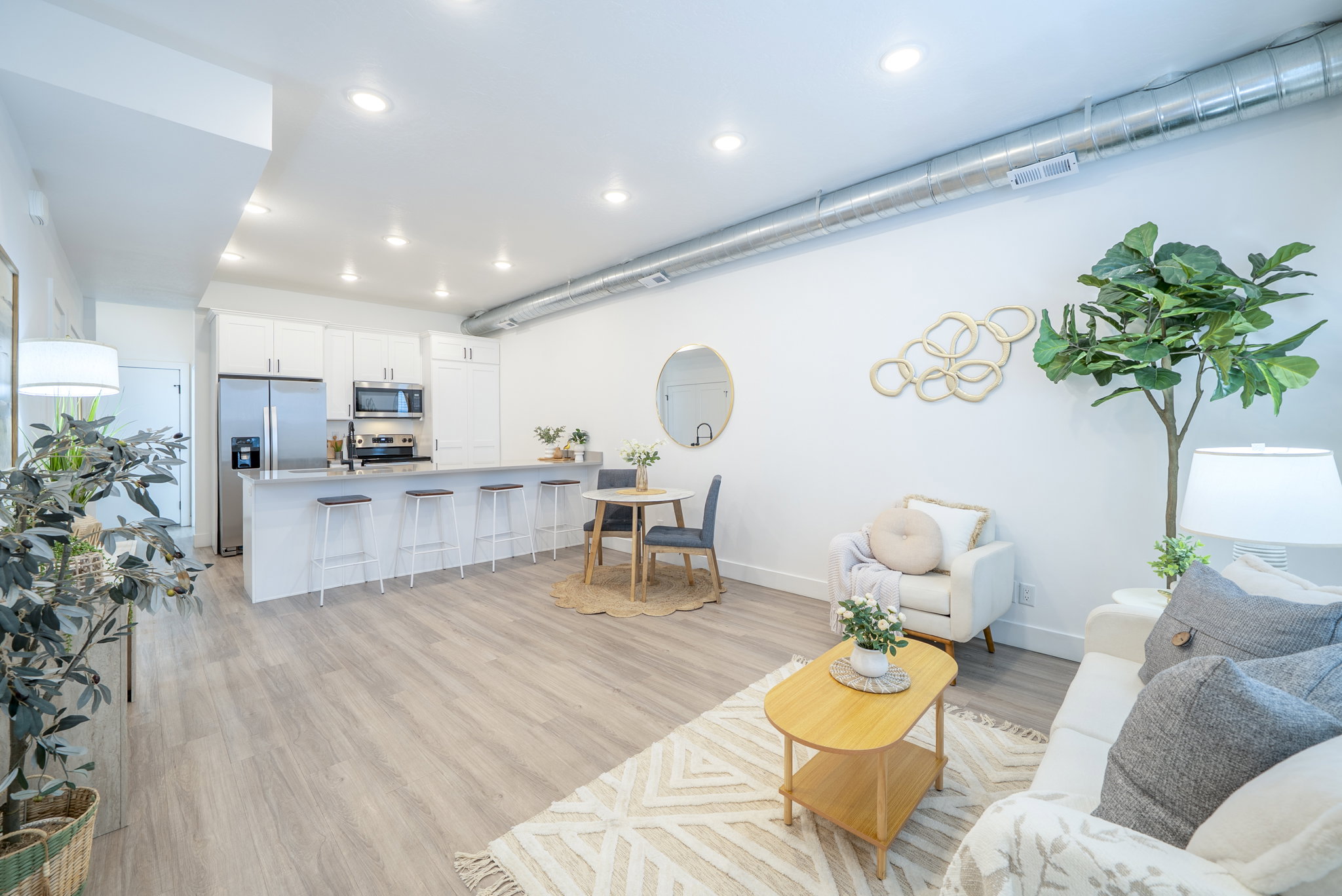 Open-concept living area featuring wood-finish flooring, recessed lighting, and exposed ductwork