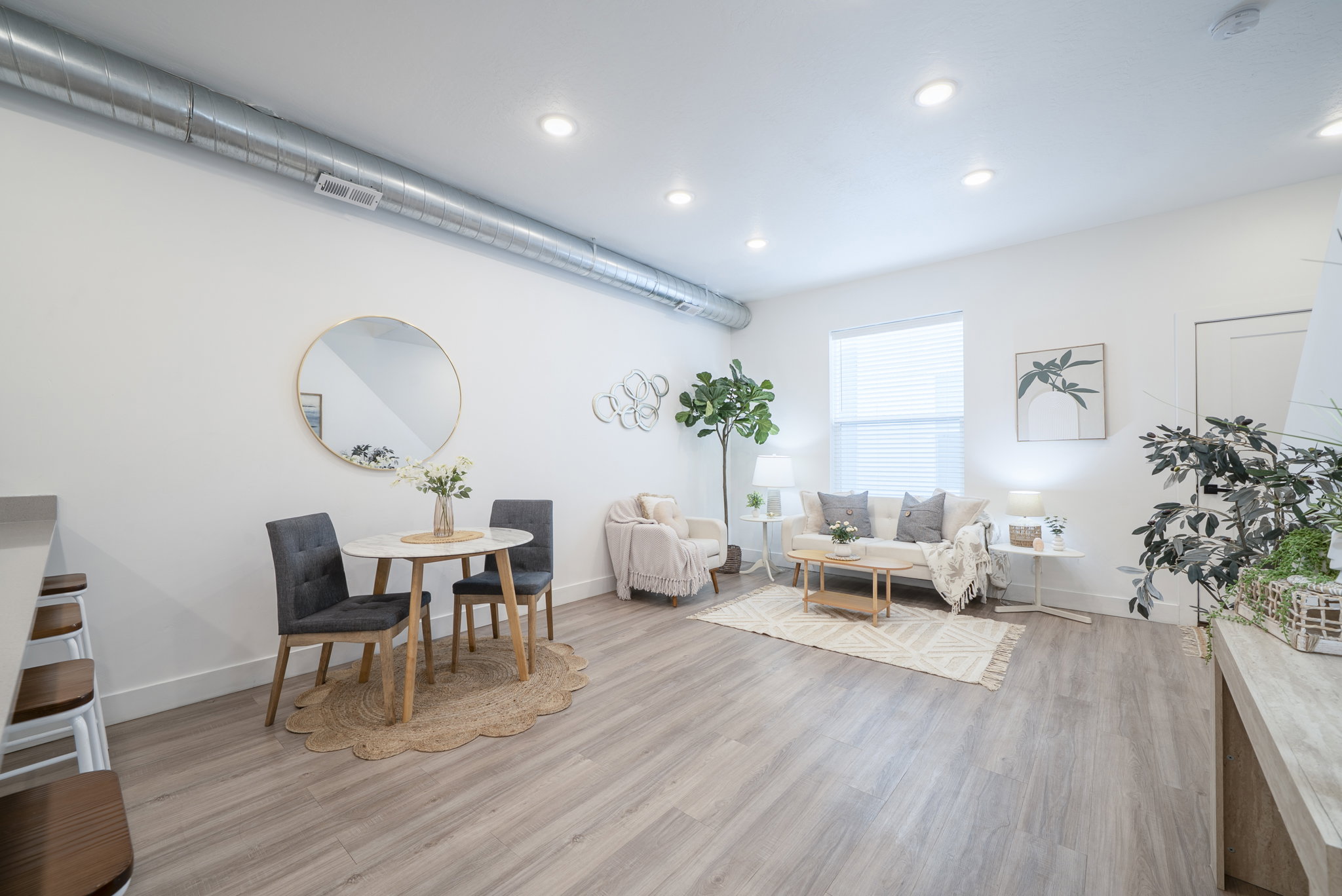 Open-concept living space featuring wood-finish flooring, recessed lighting, and a prominent exposed metallic ductwork