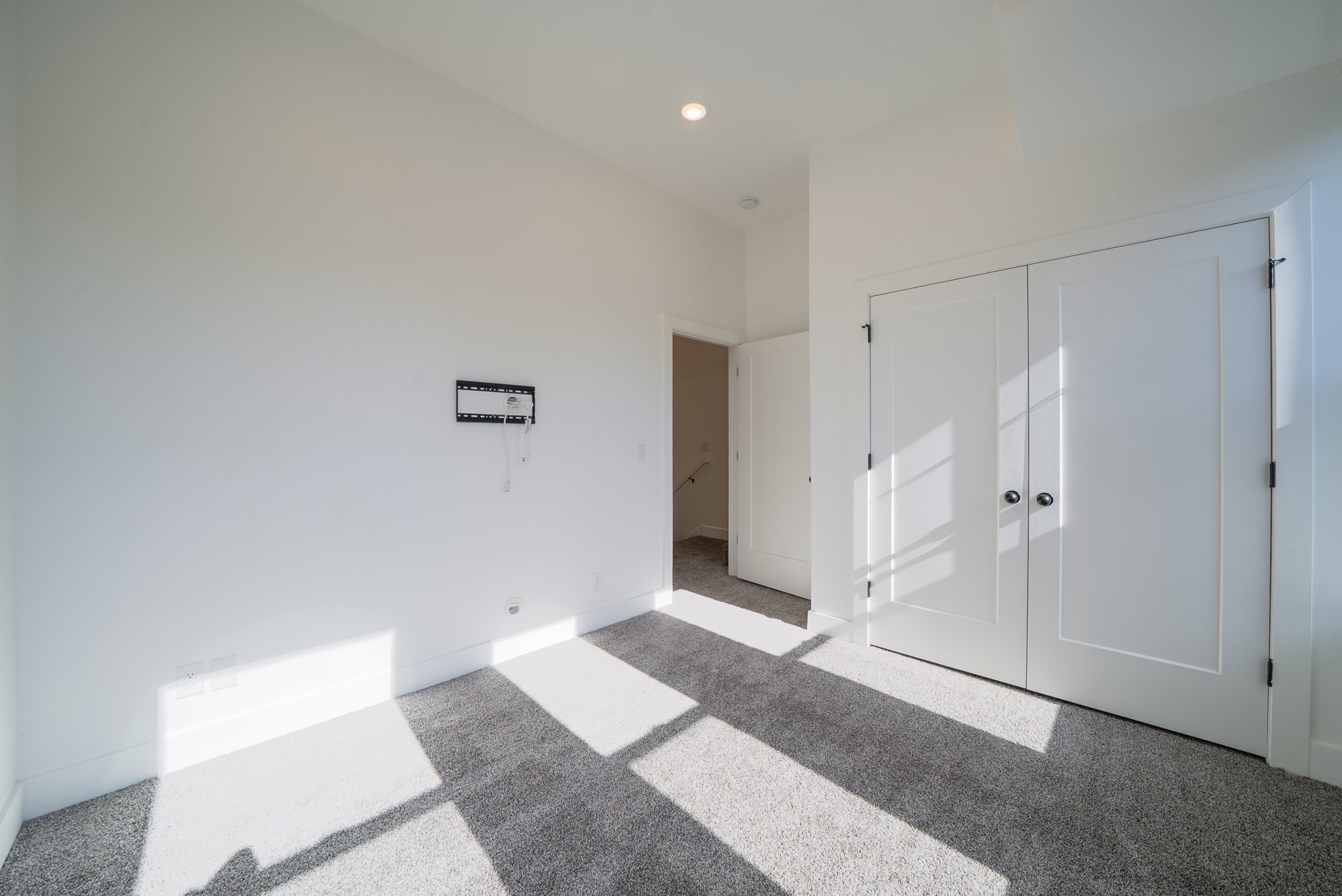 Neutral-toned wall-to-wall carpeting complements bright white walls and trim