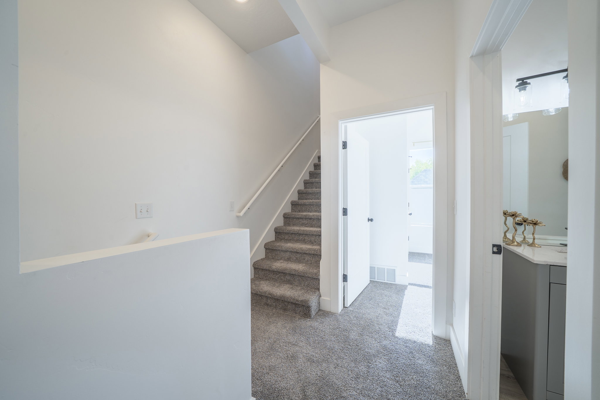 Carpeted staircase with white handrail and recessed lighting