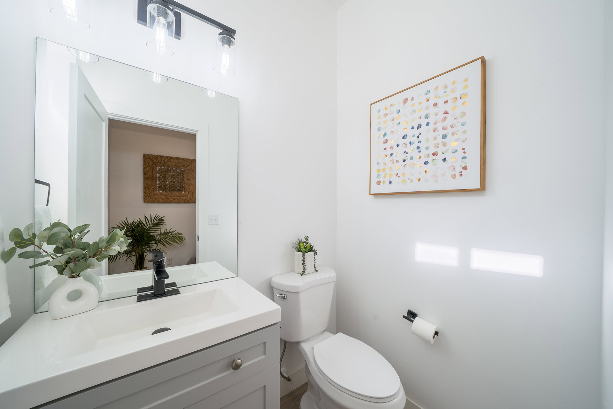 Bathroom featuring a modern vanity with integrated sink, black matte faucet, and rectangular mirror