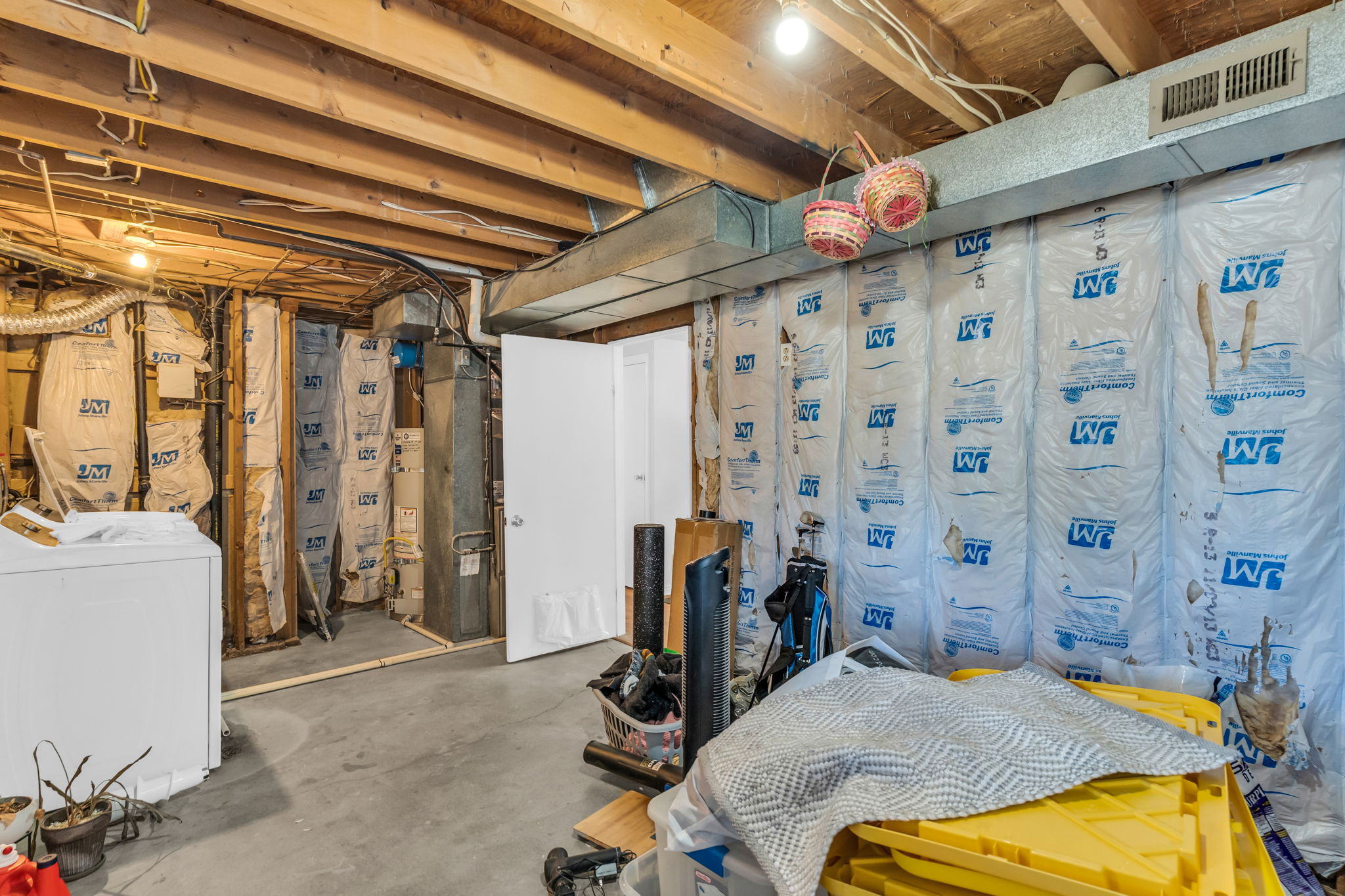 Unfinished basement featuring exposed wood joists, concrete flooring, and visible insulation