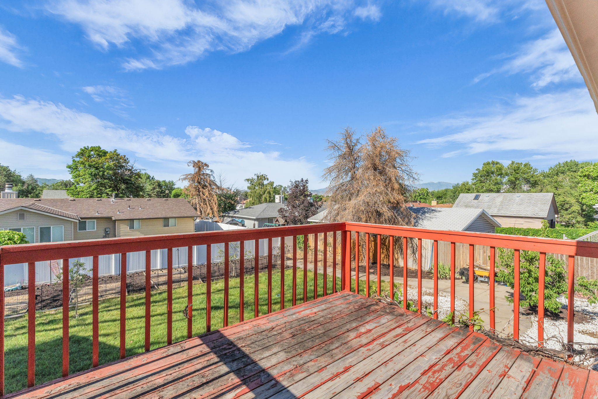 Outdoor wooden deck with red railings and surrounding landscaping