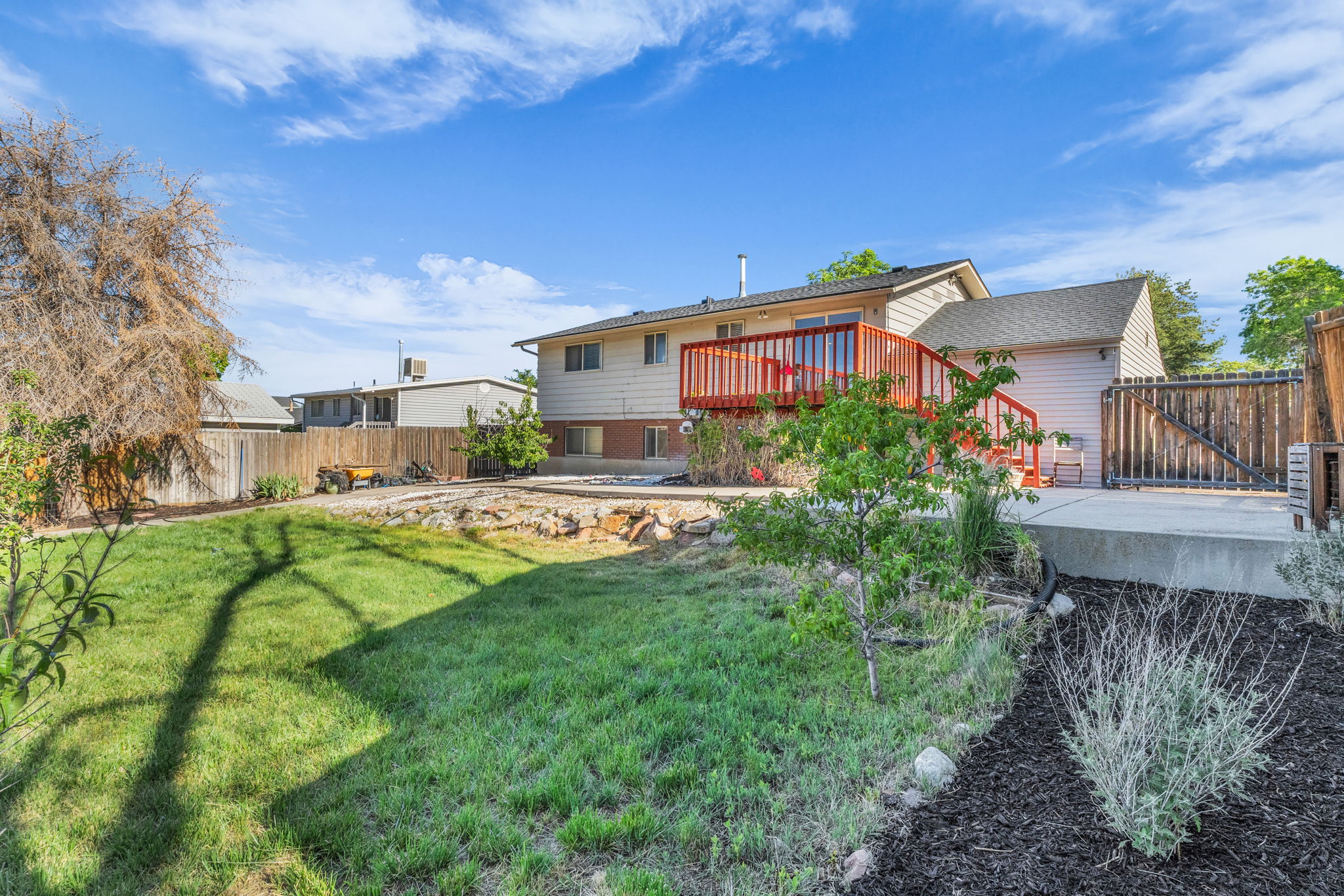 Expansive backyard featuring a green lawn, wood fence perimeter, and a raised concrete patio