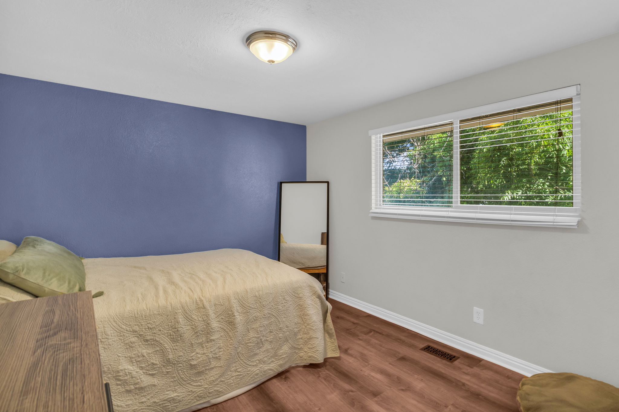 Room featuring a window with horizontal blinds, wood-finish flooring, and a flush mount ceiling light fixture