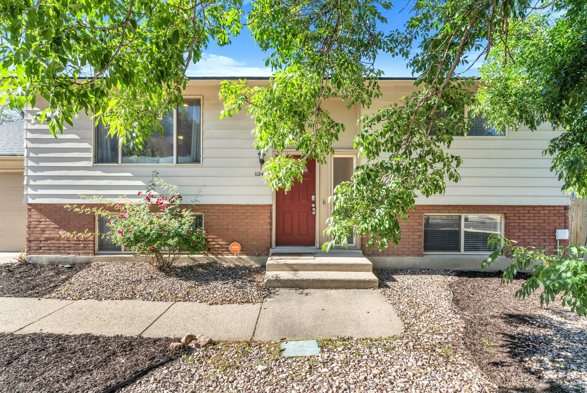 Split-level residence featuring a red entry door and white siding