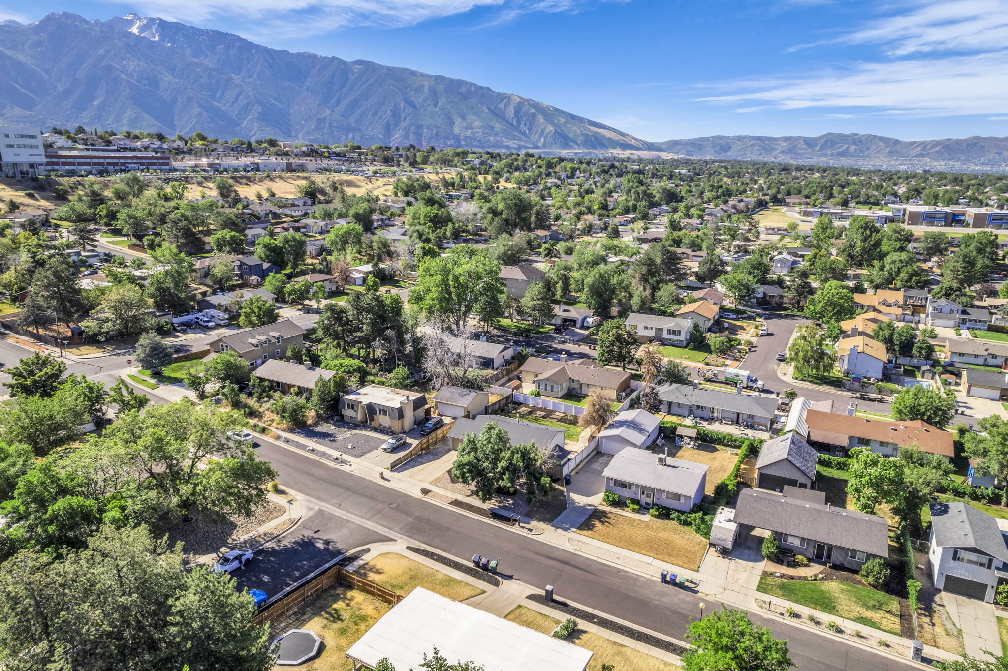 Residential neighborhood featuring an expansive mountain backdrop, mature trees, and paved streets