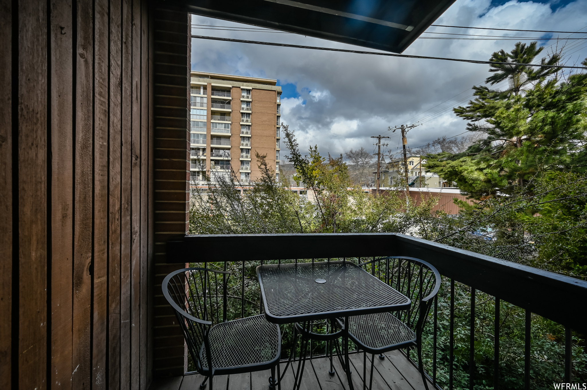Private balcony featuring wood-finish siding, dark-toned railing, and wood-finish decking