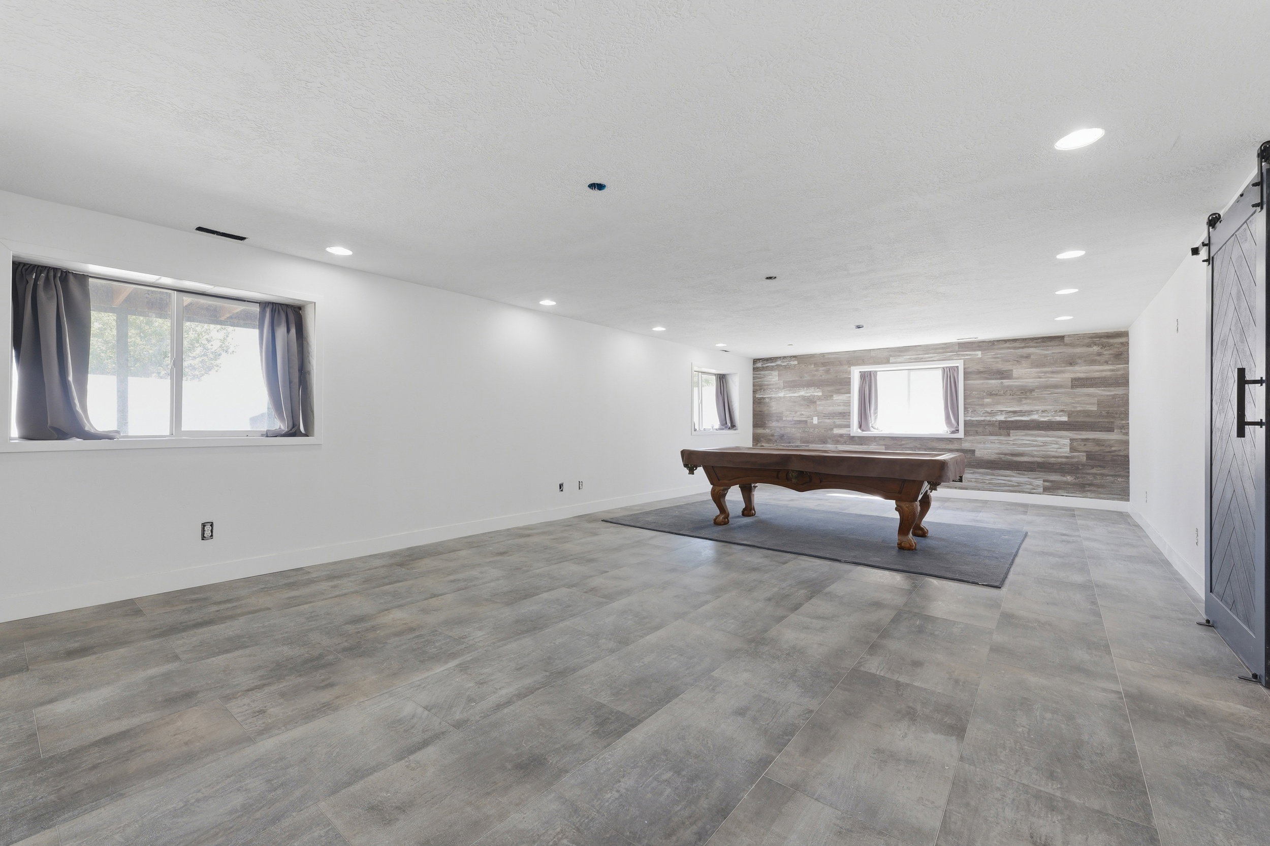 Spacious room featuring wood-finish tile flooring and recessed lighting