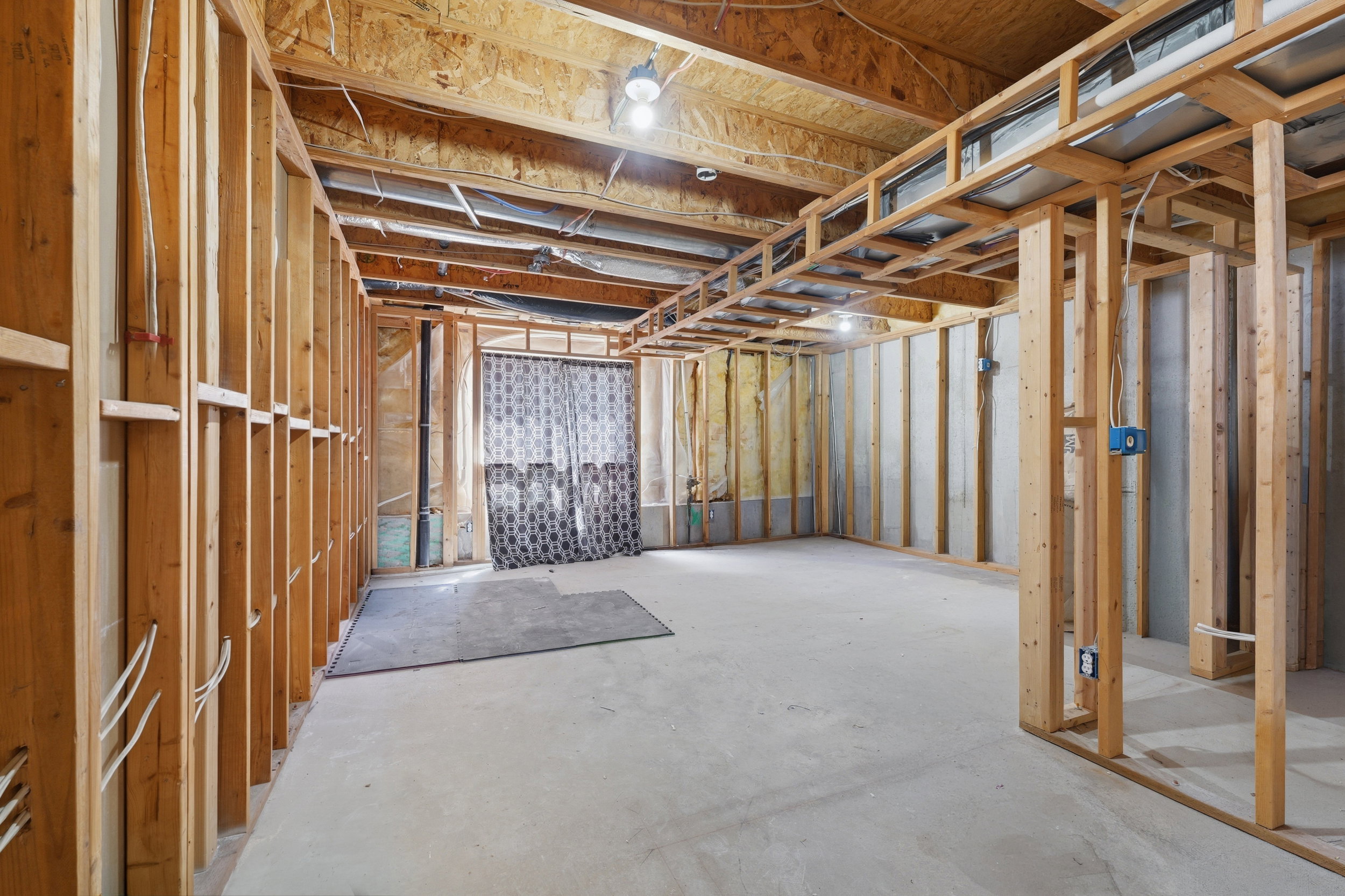 Unfinished basement bedroom featuring exposed wood framing, concrete flooring, and exposed ceiling joists