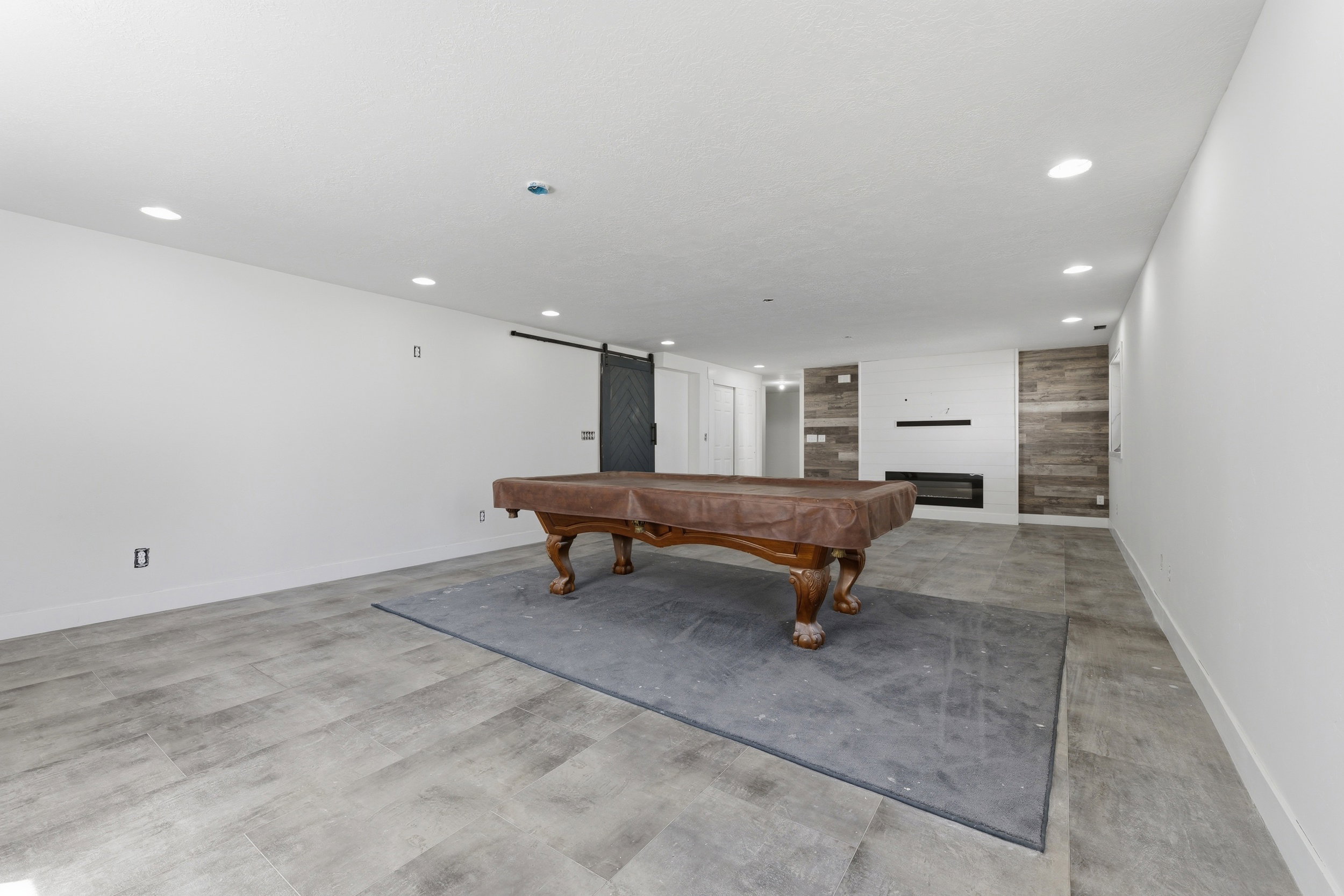Spacious room featuring light wood-finish flooring, recessed lighting, and a modern fireplace with a horizontal hearth