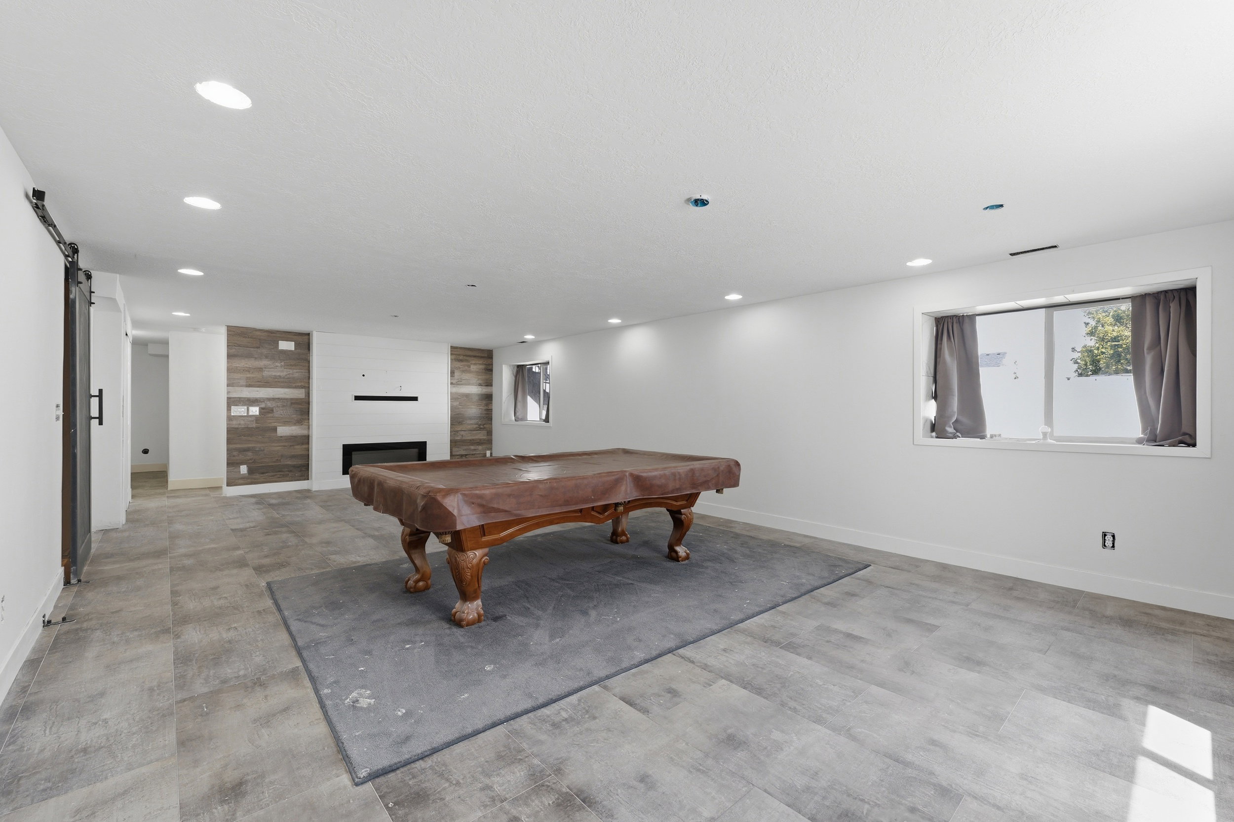 Spacious open room featuring a modern fireplace, recessed lighting, and wood-finish accent wall paneling