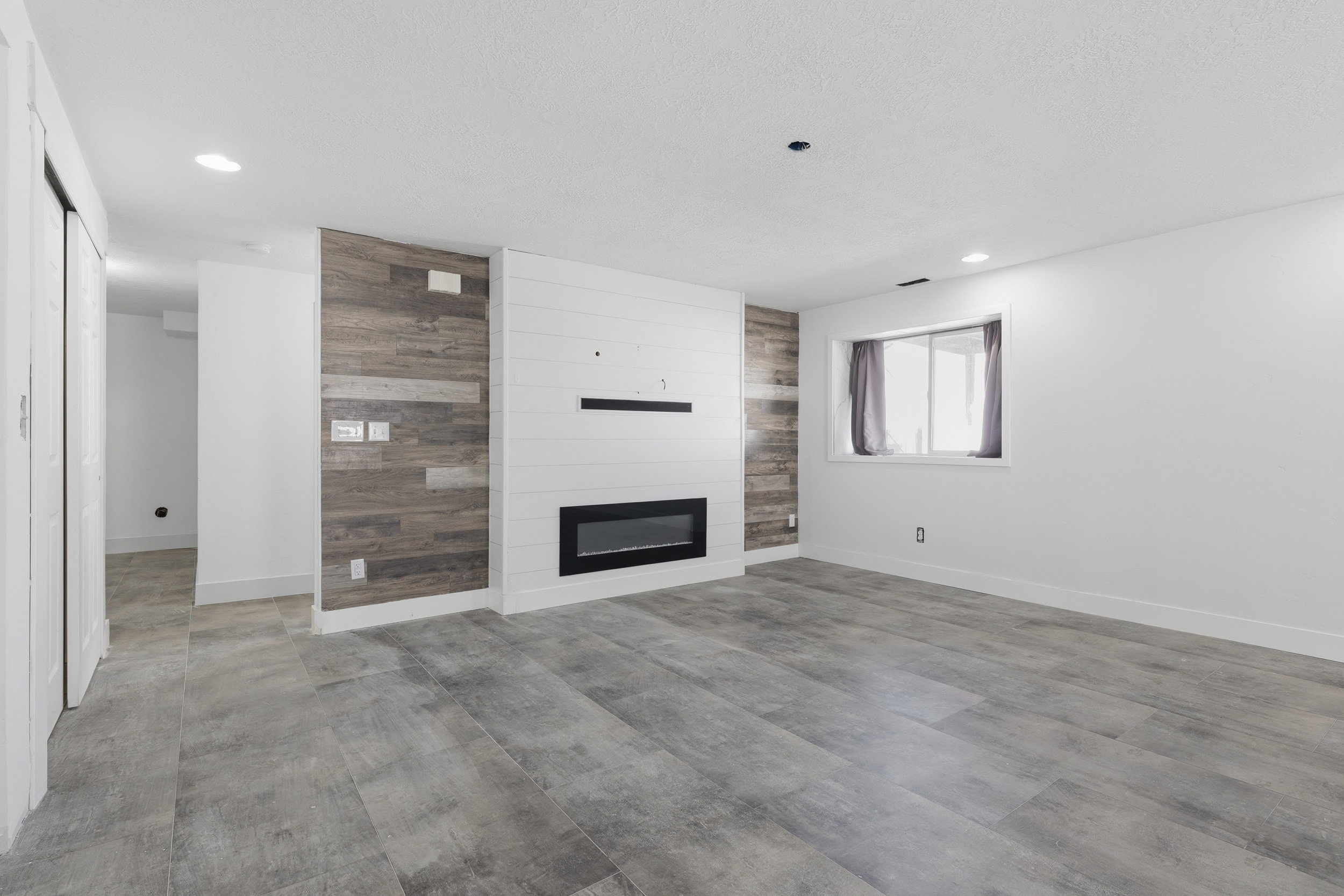 Spacious room featuring a contemporary fireplace with a linear insert and a white shiplap surround