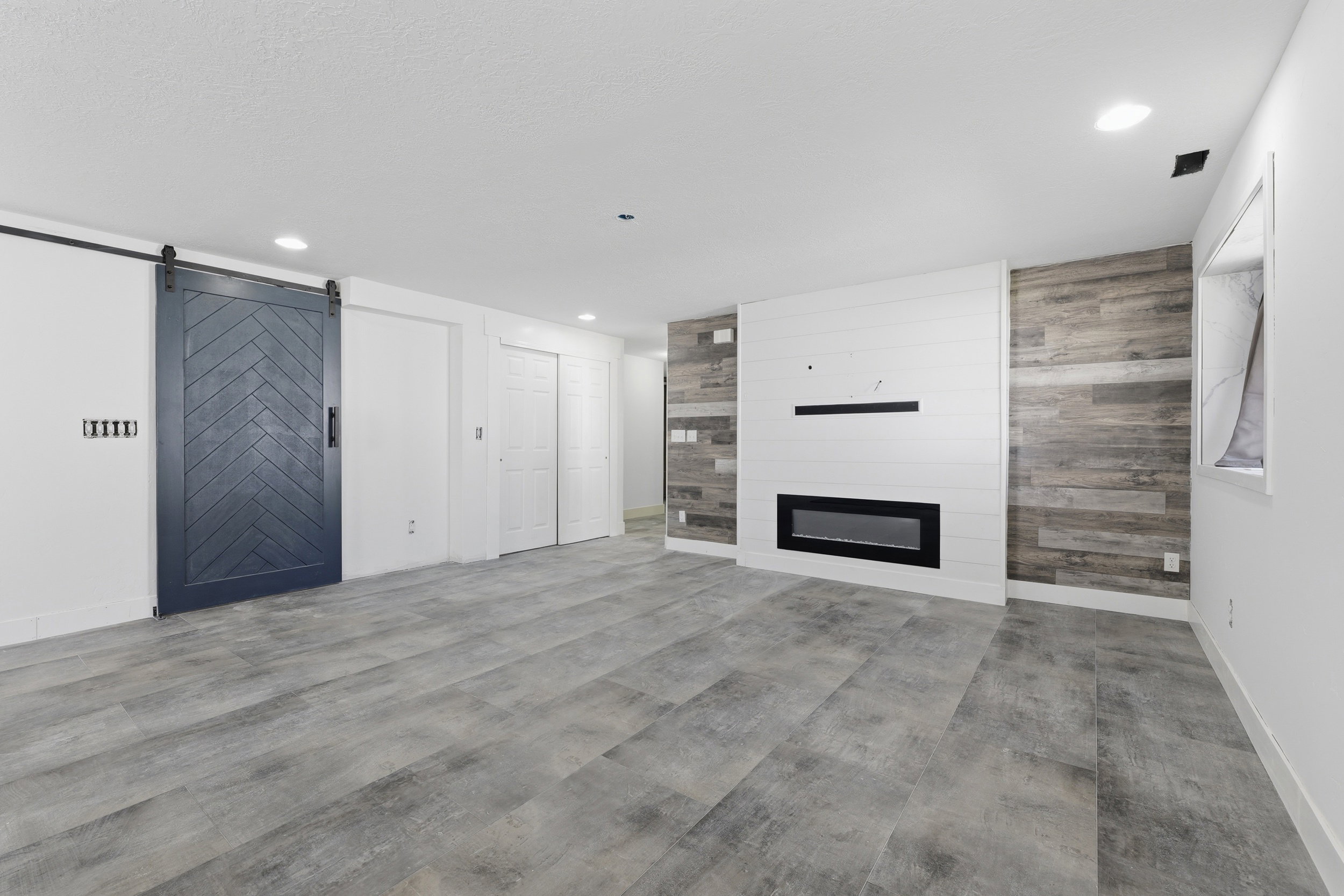 Spacious room featuring wood-finish flooring, recessed lighting, and a modern linear fireplace