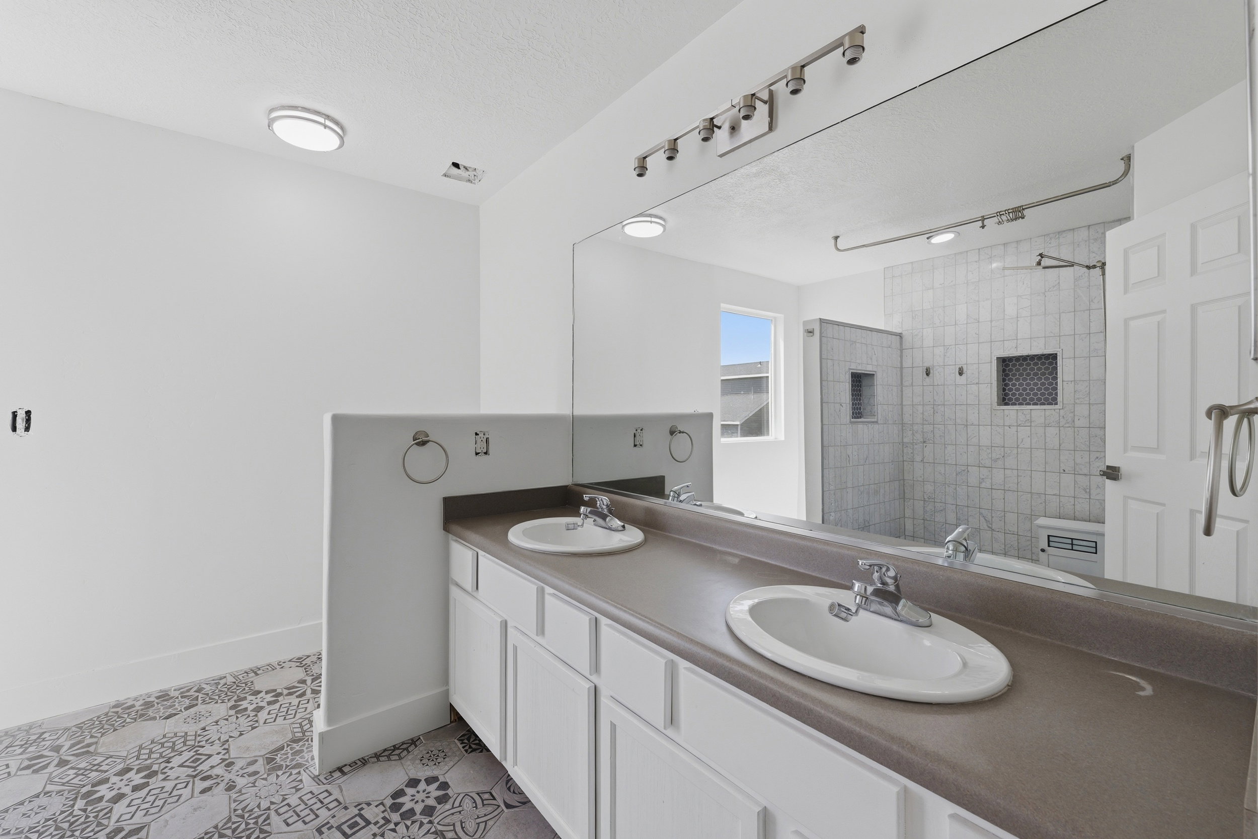 Dual basin vanity with white cabinetry and a full-width mirror