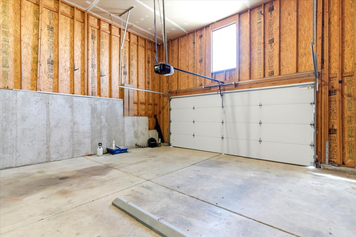 Spacious garage featuring a concrete floor, exposed wooden framing, and a white paneled garage door