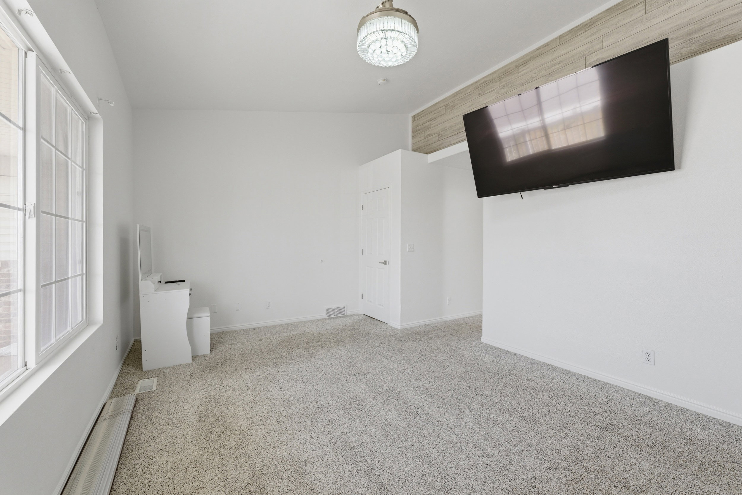 Spacious room featuring light-colored carpeting and white walls