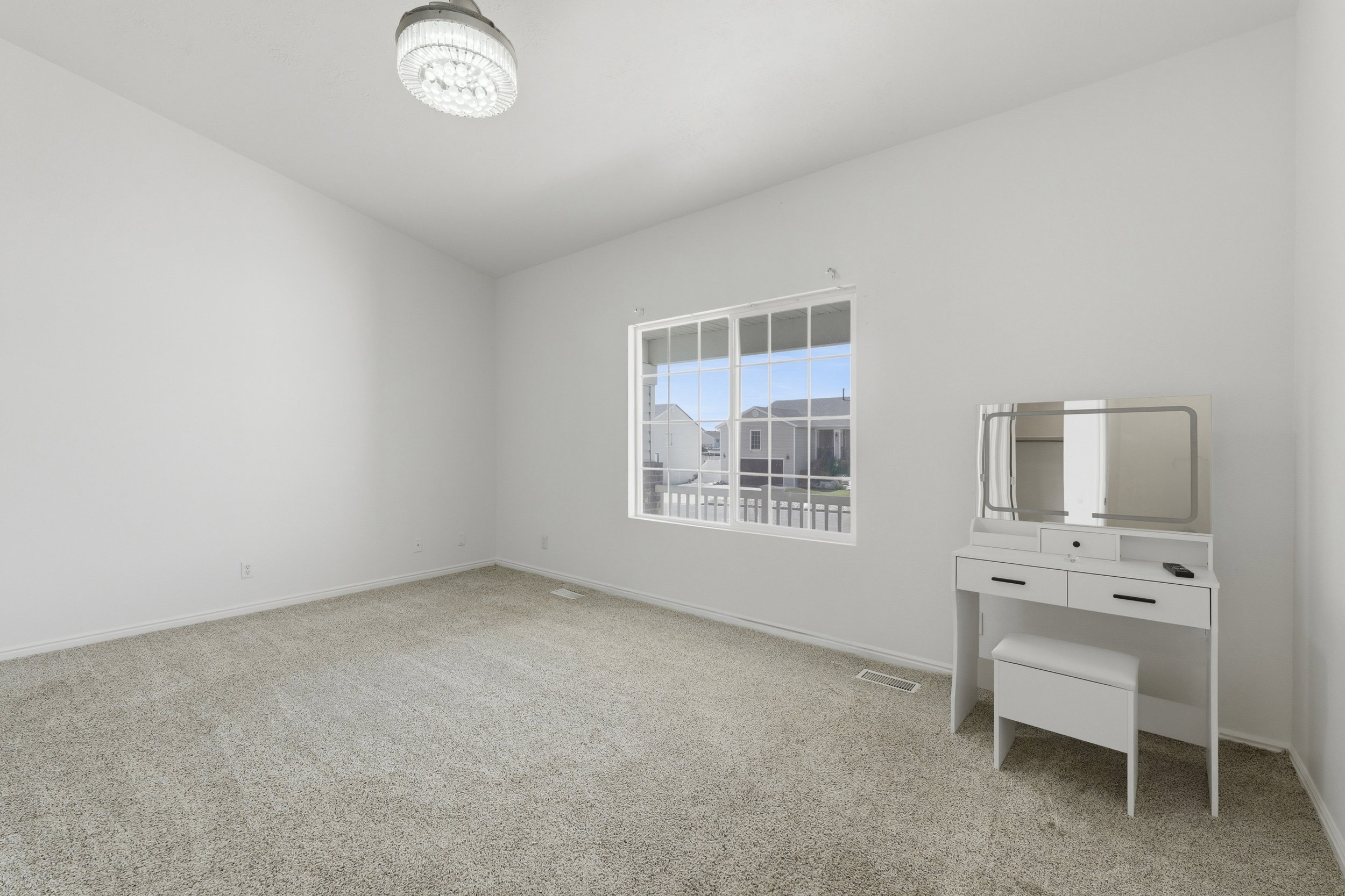 Spacious room featuring neutral carpeting, white walls, a large multi-pane window, and a contemporary flush-mount ceiling light fixture