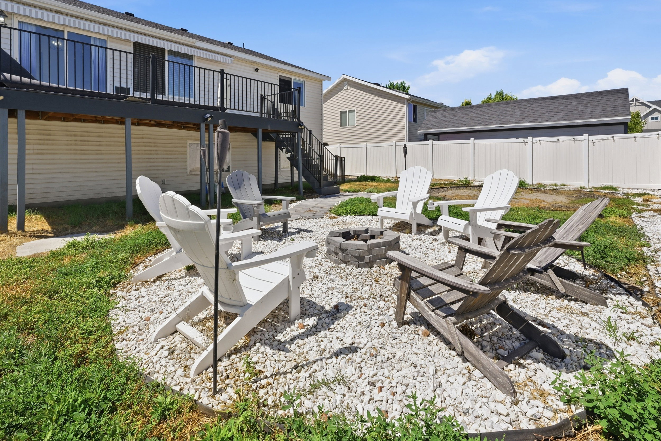 Outdoor fire pit area featuring a gravel base, a stone-block fire pit, and a surrounding lawn