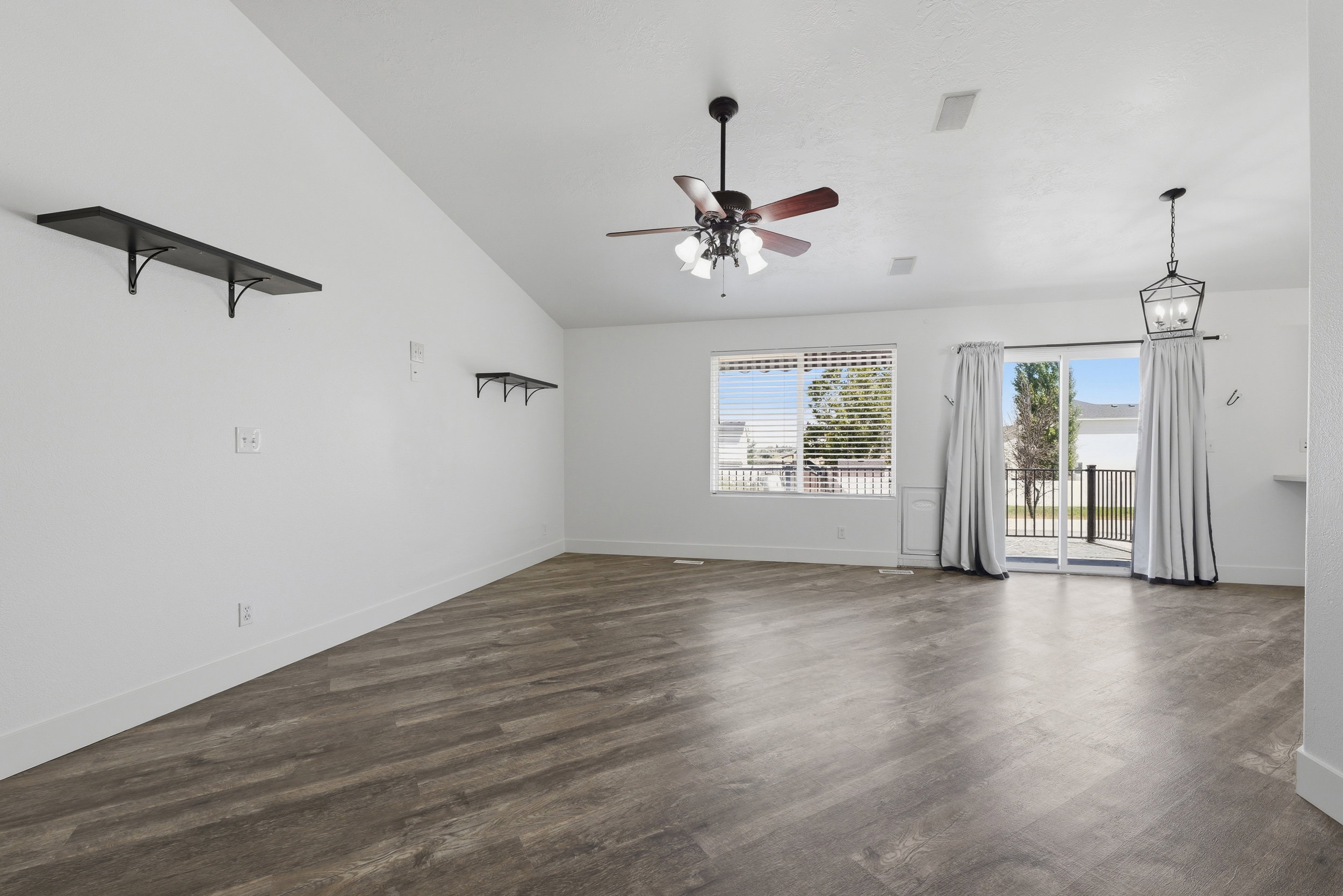 Spacious living area featuring wood-finish flooring, a vaulted ceiling, and recessed lighting