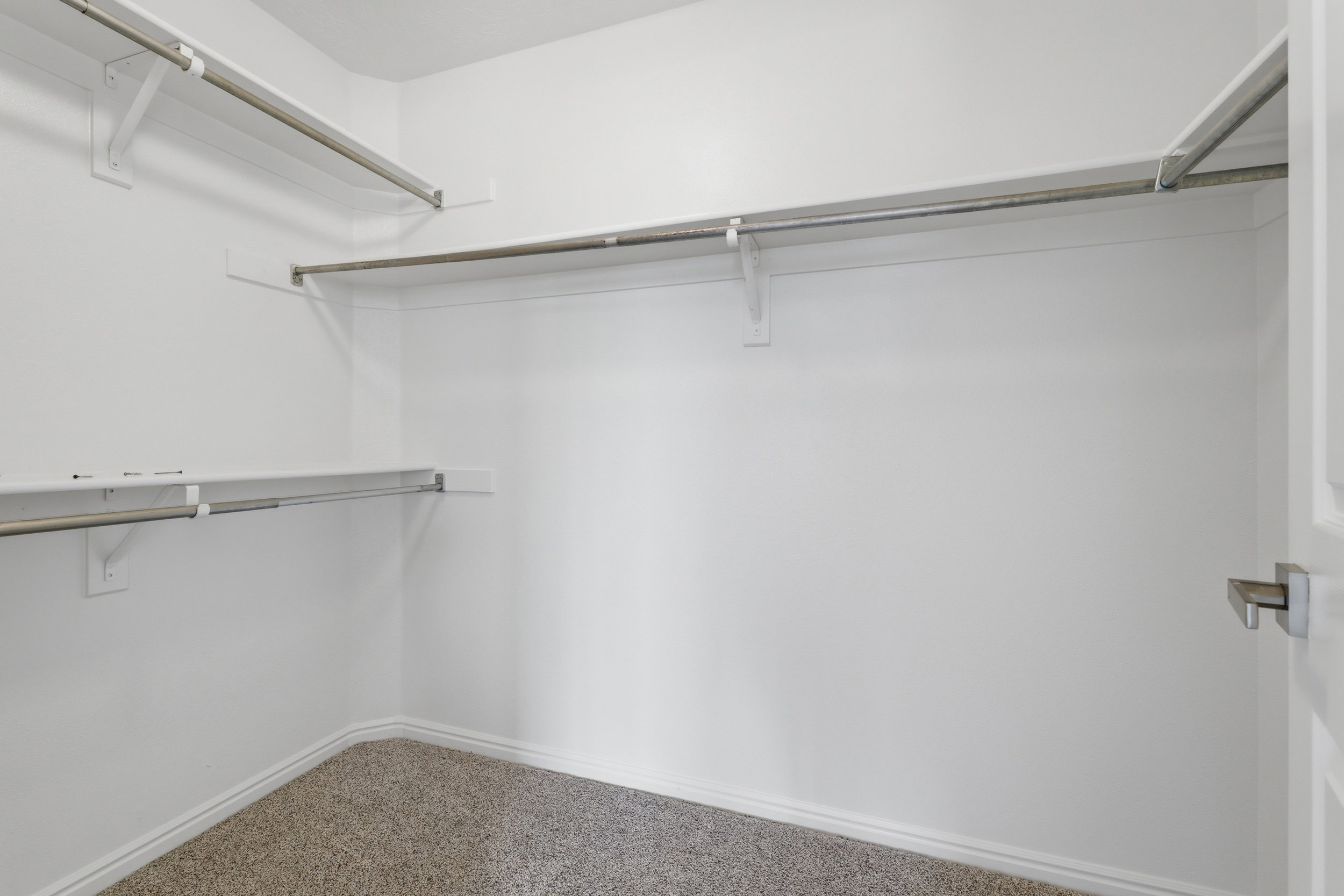 Walk-in closet featuring white walls, ample shelving, and clothing rods