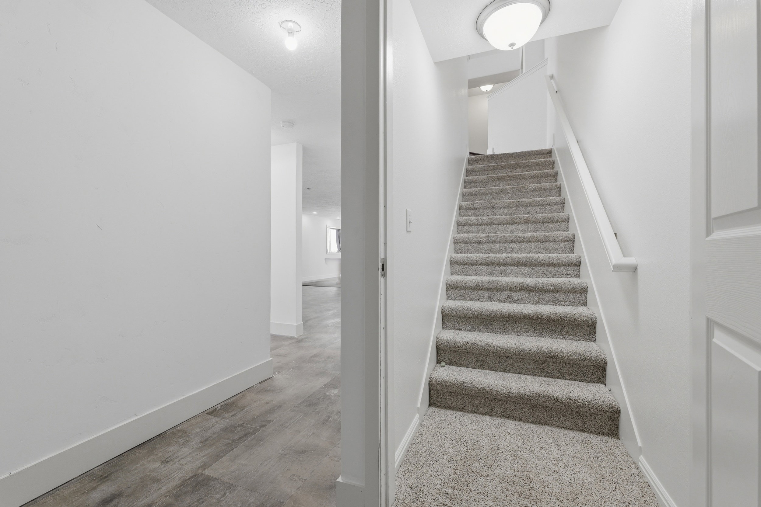 Carpeted staircase featuring a painted handrail and white walls
