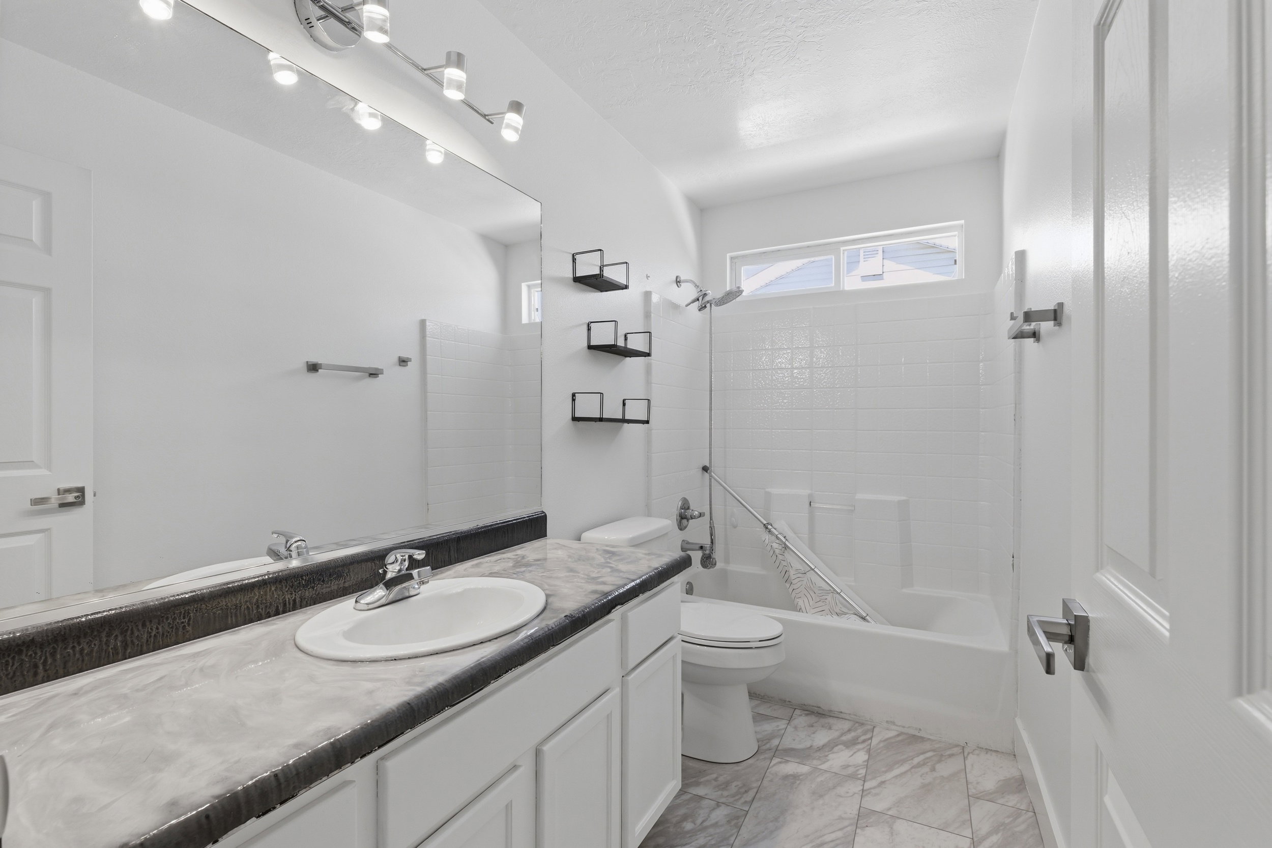 Bathroom featuring a single vanity with an oval sink, a light-toned countertop, and white cabinetry