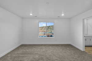 Carpeted interior space featuring a window with a distant mountain landscape, recessed lighting, and white baseboards