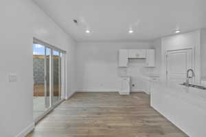 Open concept living area with wood-finish flooring, recessed lighting, and a modern kitchen