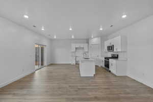 Open-concept living space featuring wood-finish flooring, recessed lighting, and a modern kitchen