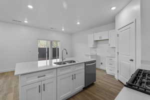 Kitchen featuring an island with double sinks, white shaker-style cabinetry, and light-toned countertops