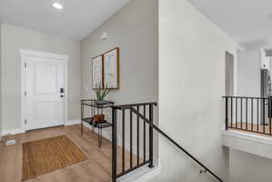 Entryway featuring a paneled white door with smart lock, recessed lighting, and wood-finish flooring