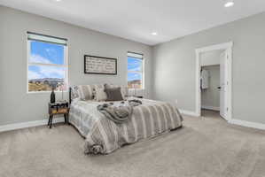 Spacious room featuring light gray wall paint, recessed lighting, two windows with roller shades, and a closet with a white door and black hardware