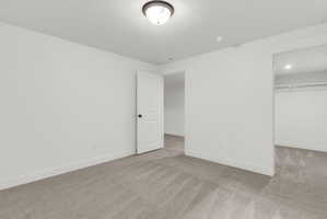 Room featuring light gray carpet flooring, white walls, and a white interior door with black hardware