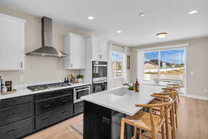 Modern kitchen featuring two-tone cabinetry, stainless steel appliances, a gas cooktop, and a spacious island with an integrated sink