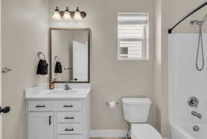 Bathroom featuring a white vanity with black hardware, a rectangular framed mirror, three-light vanity fixture, and a standard tub/shower combination with a curved shower rod