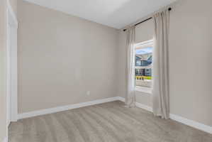 Neutral-toned room featuring a single window with curtain rods, light wall paint, white trim, and gray carpeting
