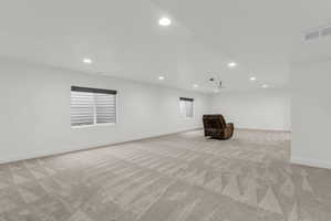 Spacious room featuring light-colored patterned carpeting, white walls, and recessed ceiling lighting