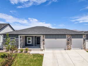 Modern residence featuring a stone and siding facade, a covered entry porch, and an attached two-car garage