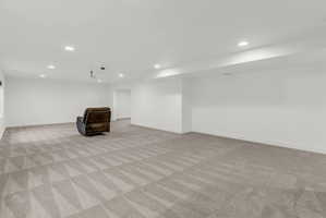 Spacious room featuring light-toned geometric pattern carpeting, recessed lighting, and crisp white walls