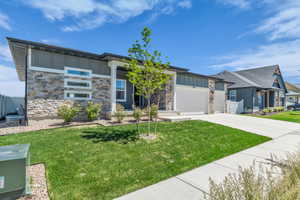 Modern exterior featuring stacked stone accents, horizontal siding, a white garage door, and a concrete driveway
