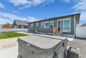 Expansive backyard featuring a covered hot tub, paver patio, concrete patio, and a manicured lawn